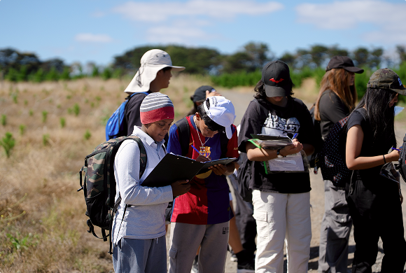 A group of school students writing notes on a guided tour of Yeowarra farm.