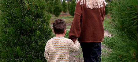 A mother and son walk hand in hand through the pine trees at Yeowarra.